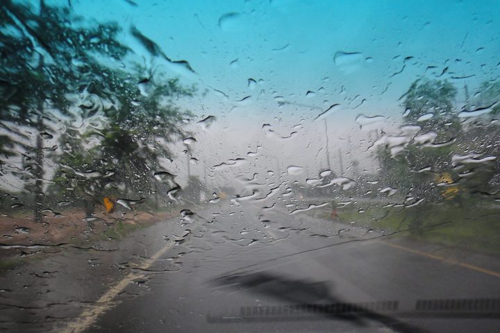 Rain beading on a windscreen with the wiper blade across the glass, the road ahead blurred